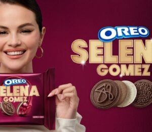 Photo shows Selena Gomez on a purple background holding up the new Oreo cookies she helped to design