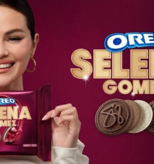 Photo shows Selena Gomez on a purple background holding up the new Oreo cookies she helped to design