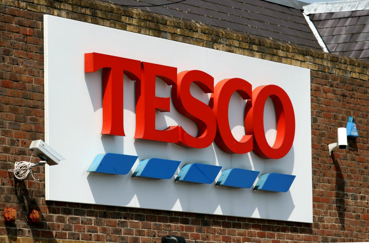 Photo shows a large Tesco sign on the side of a red brick building