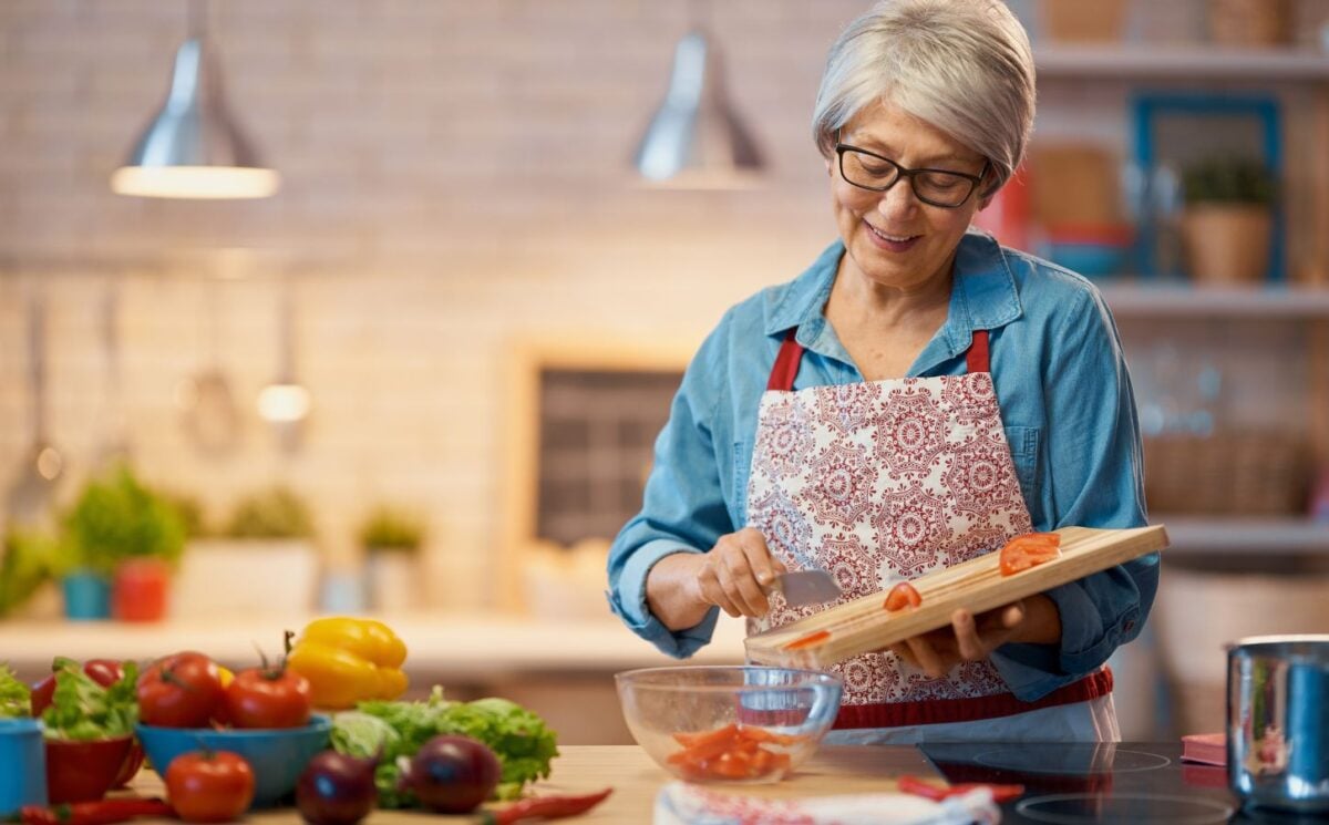 Photo shows a woman chopping vegetables in her kitchen