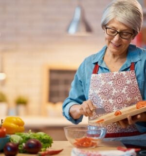 Photo shows a woman chopping vegetables in her kitchen