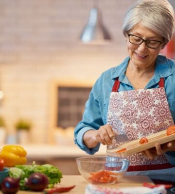 Photo shows a woman chopping vegetables in her kitchen