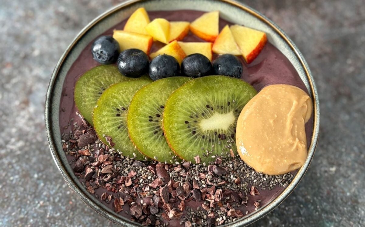 A vegan acai smoothie bowl topped with nectarine, blueberries, and kiwi, a high protein vegan breakfast