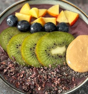 A vegan acai smoothie bowl topped with nectarine, blueberries, and kiwi, a high protein vegan breakfast