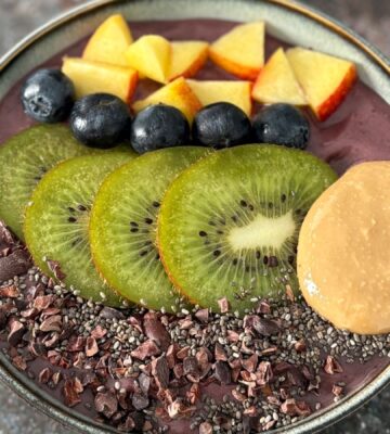 A vegan acai smoothie bowl topped with nectarine, blueberries, and kiwi, a high protein vegan breakfast