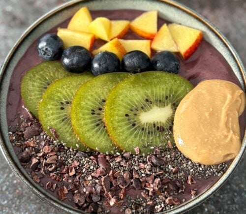 A vegan acai smoothie bowl topped with nectarine, blueberries, and kiwi, a high protein vegan breakfast