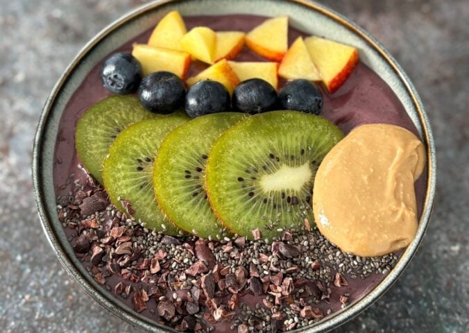 A vegan acai smoothie bowl topped with nectarine, blueberries, and kiwi, a high protein vegan breakfast