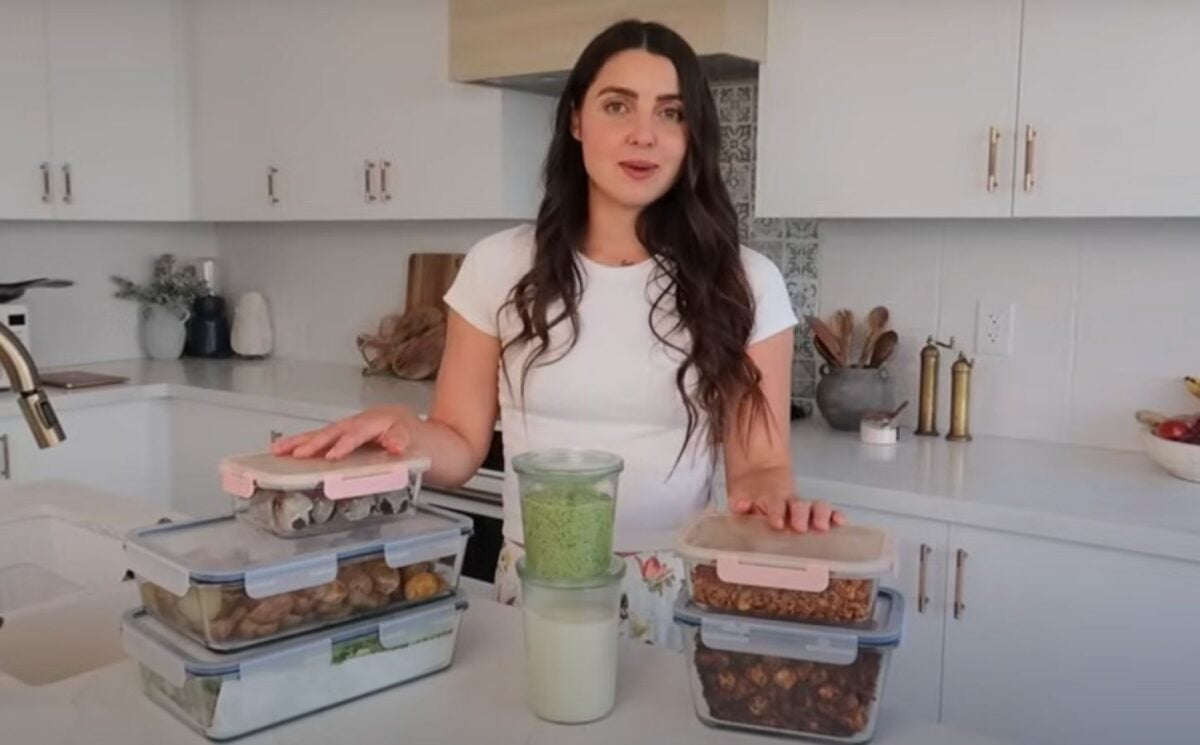 Stephanie Manzinali of That Vegan Babe stands in her kitchen with prepped vegan sauces, proteins, and snacks, ready to create high-protein meals in under two hours using her flexible mix-and-match method.