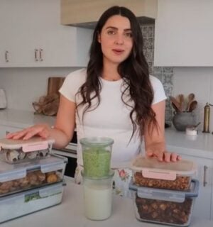 Stephanie Manzinali of That Vegan Babe stands in her kitchen with prepped vegan sauces, proteins, and snacks, ready to create high-protein meals in under two hours using her flexible mix-and-match method.