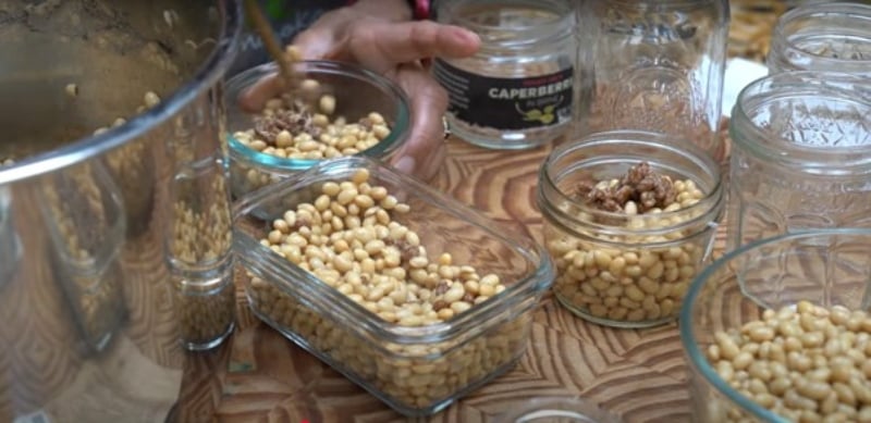Several glass containers and a metal pot are filled with soybeans that will be left to ferment to make natto.