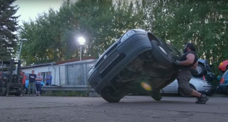 People gather to watch as vegan strongman Patrik Baboumian flips a car.