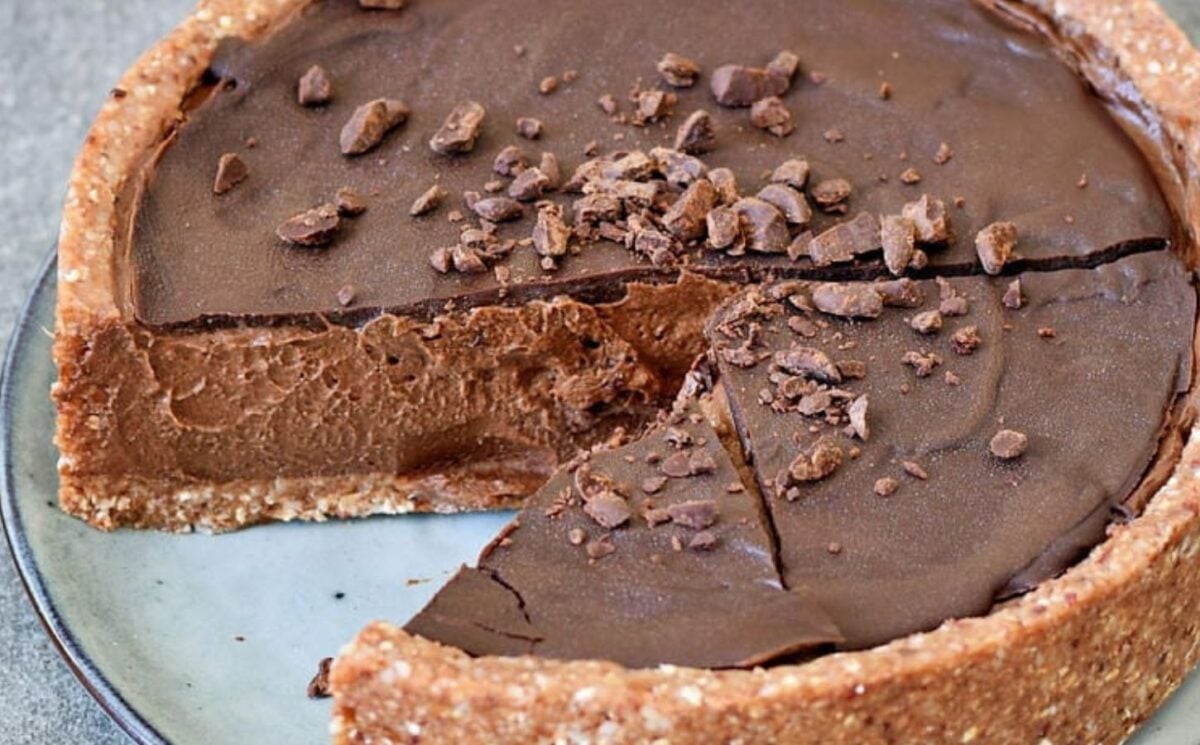 A picture of a dense vegan chocolate pie made with a thick nutty crust and a chocolate drizzle as part of sweet vegan pie recipes