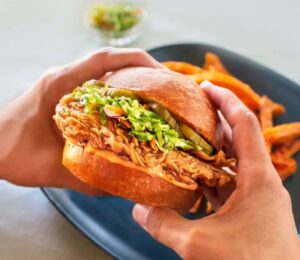 Photo shows someone holding a chicken burger made with cultivated meat from UPSIDE Foods