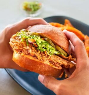Photo shows someone holding a chicken burger made with cultivated meat from UPSIDE Foods