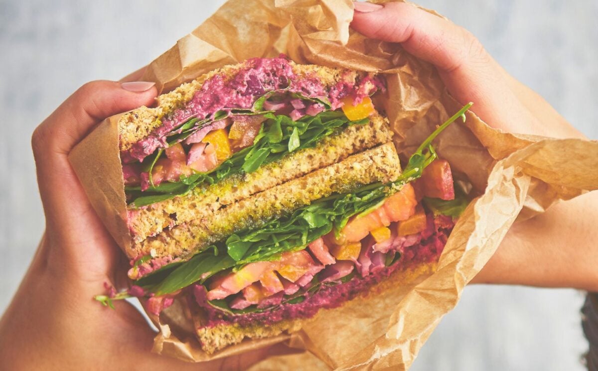 an epic veggie sandwich with red onion, tomato, yellow bell pepper, and more