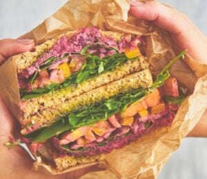 an epic veggie sandwich with red onion, tomato, yellow bell pepper, and more