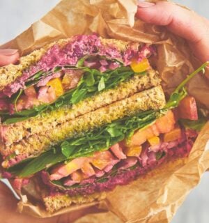 an epic veggie sandwich with red onion, tomato, yellow bell pepper, and more