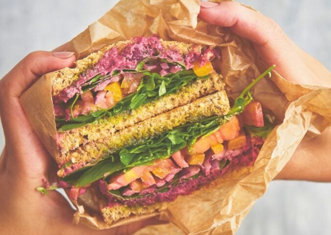 an epic veggie sandwich with red onion, tomato, yellow bell pepper, and more