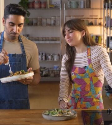 Dr. Rupy Aujla and Sophie Waplington stand by a counter cooking high-protein vegan work lunches