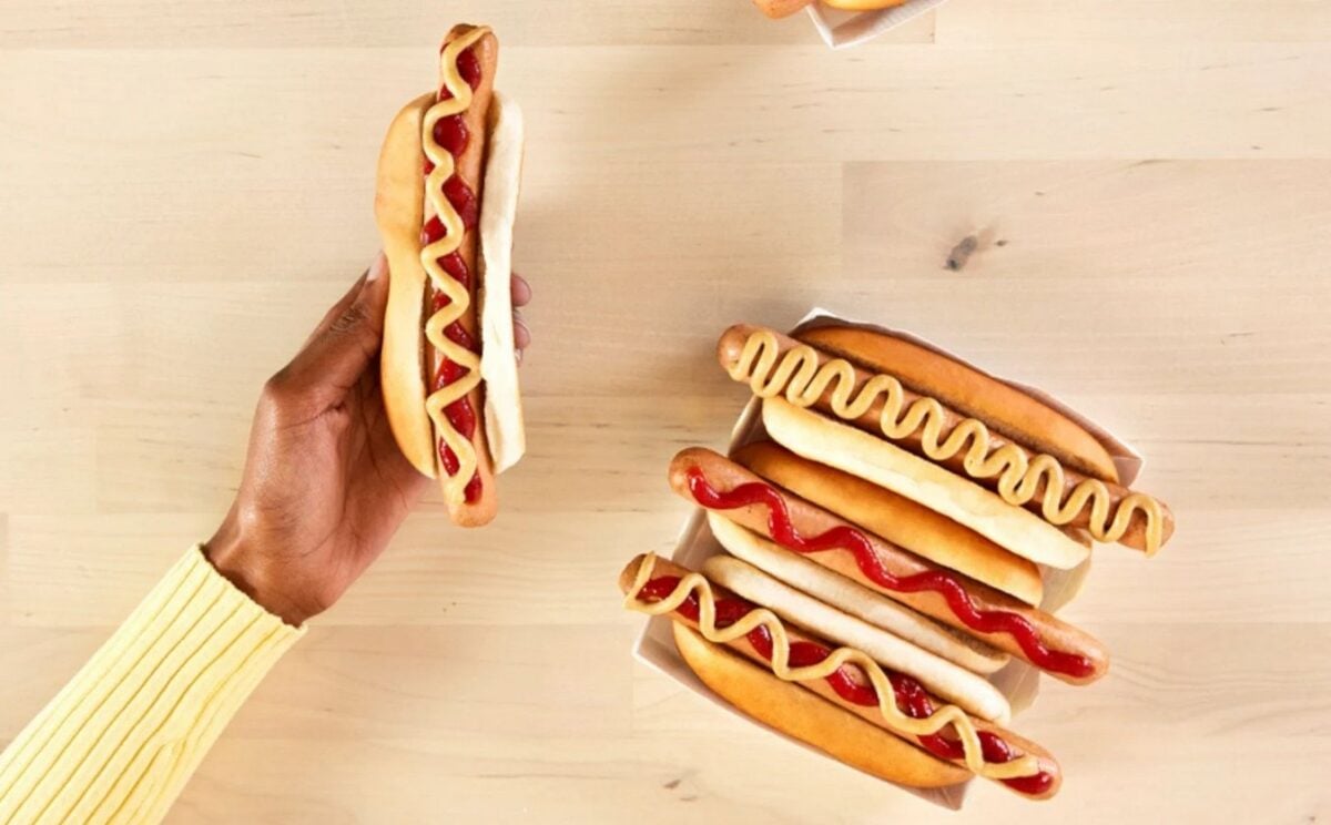 Photo shows someone's hand as they hold out a vegan hotdog from IKEA