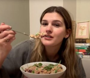 Nicole Whittle holds a colorful vegan couscous bowl packed with chickpeas, beetroot, and greens during her plant-based meal prep for the week.