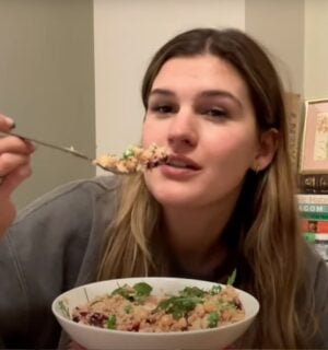 Nicole Whittle holds a colorful vegan couscous bowl packed with chickpeas, beetroot, and greens during her plant-based meal prep for the week.