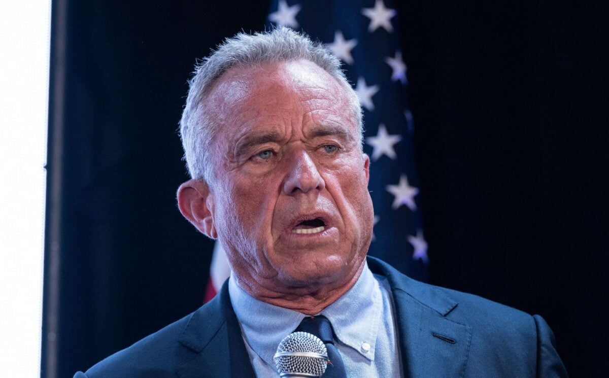 Photo shows RFK Jr speaking into a microphone in front of a US flag