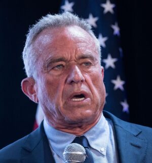 Photo shows RFK Jr speaking into a microphone in front of a US flag