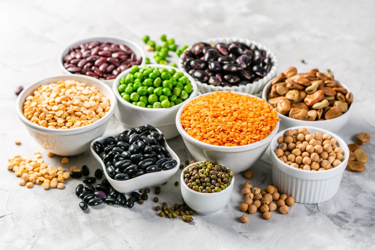 A selection of legumes like peas, lentils, and beans, which are often vegan protein sources for plant-based athletes