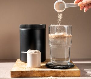 A person pouring a scoop of creatine into a glass of water