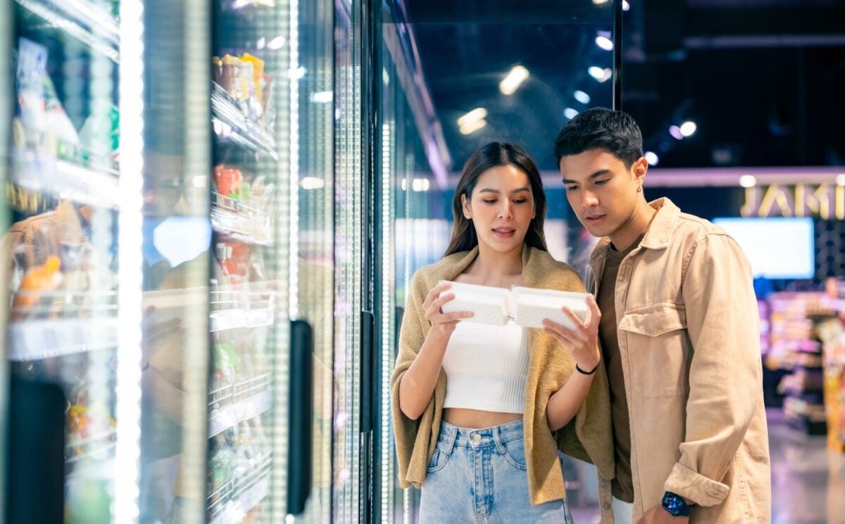 Photo shows a young couple in the supermarket reading the back of a packet together