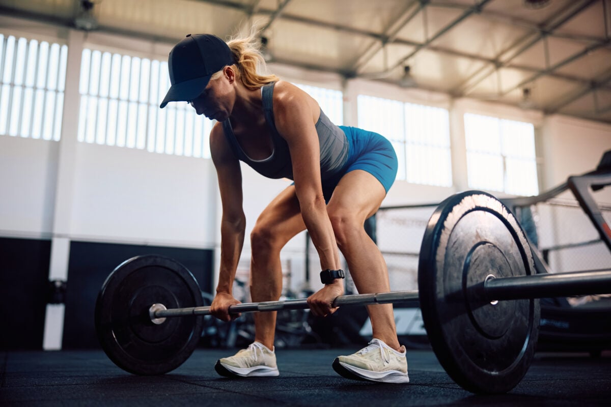 Photo shows a woman lifting a barbell in a gym