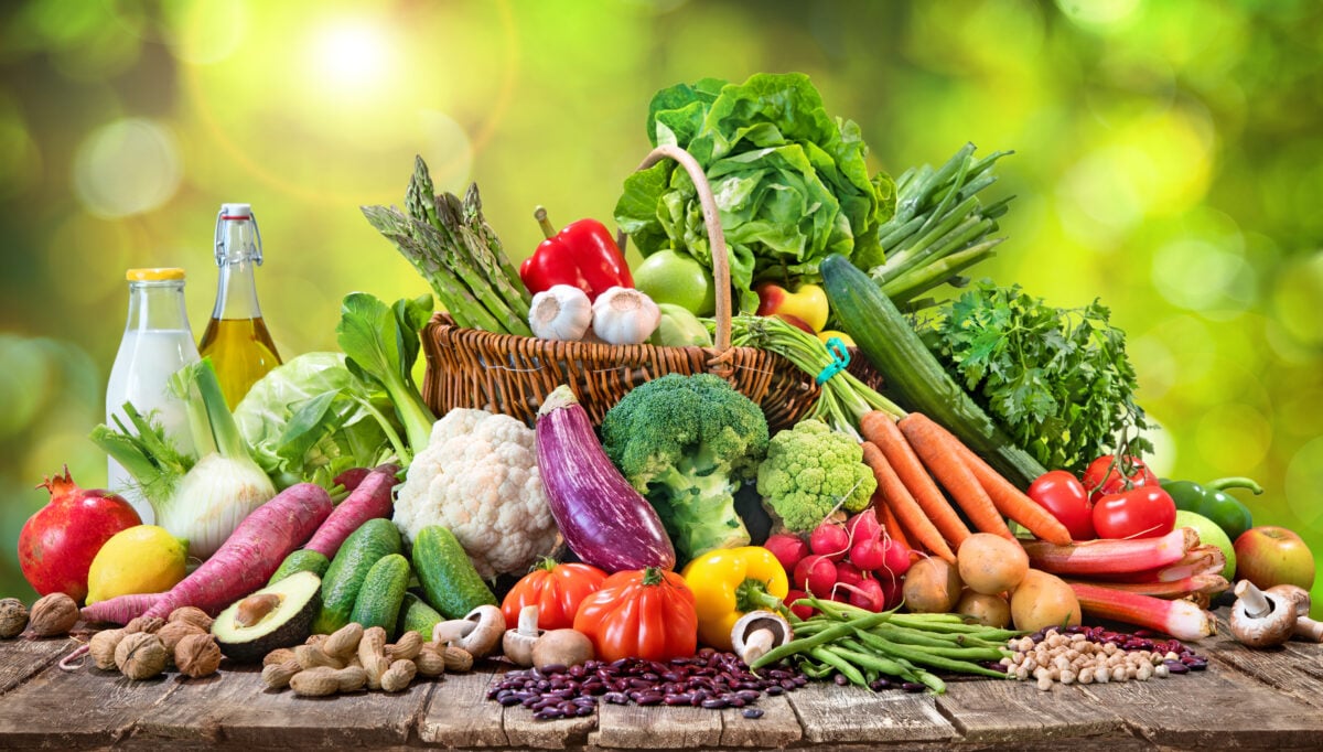 Photo shows an assortment of fresh organic vegetables and fruits in wicker basket