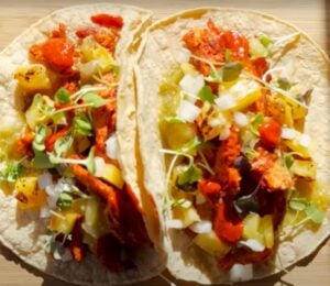Two vegan tacos on a wooden chopping board