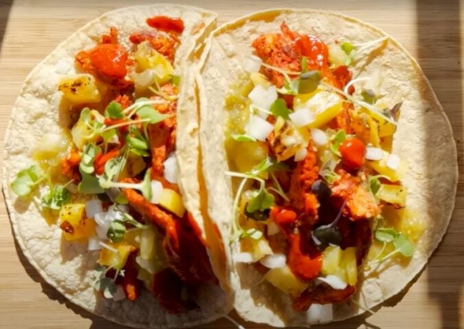 Two vegan tacos on a wooden chopping board