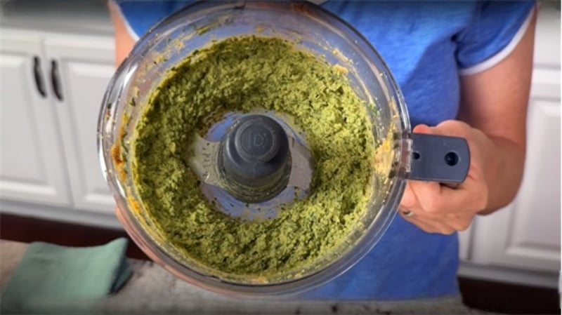 Close-up of freshly blended green goddess hummus in a food processor, held by Jill Dalton