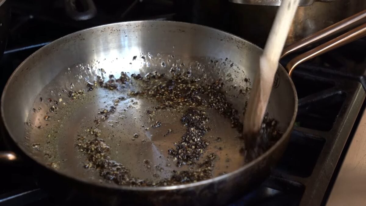 Miyoko Schinner fries the peppercorns she just crushed with a wine bottle in a stainless steel pan drizzled with olive oil and stirs it with a wooden spoon