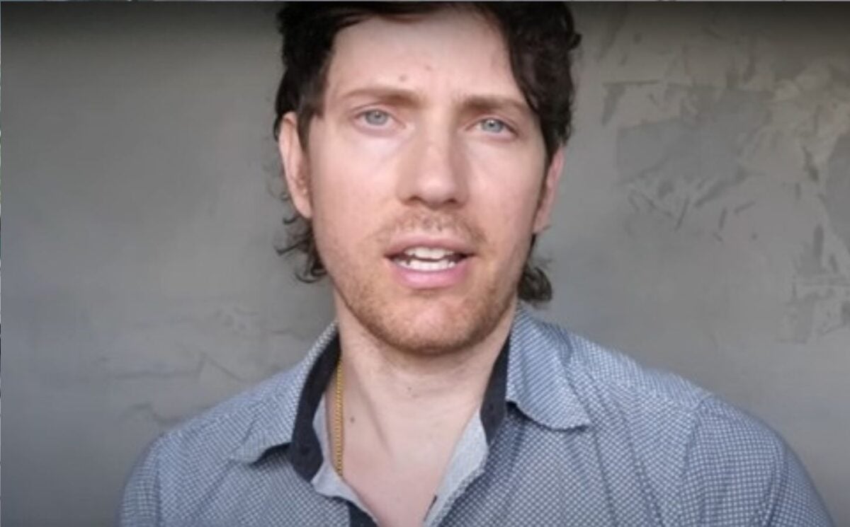 Mic the Vegan speaks to the camera in front of a grey background in a still from his video about vegan collagen