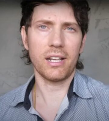 Mic the Vegan speaks to the camera in front of a grey background in a still from his video about vegan collagen