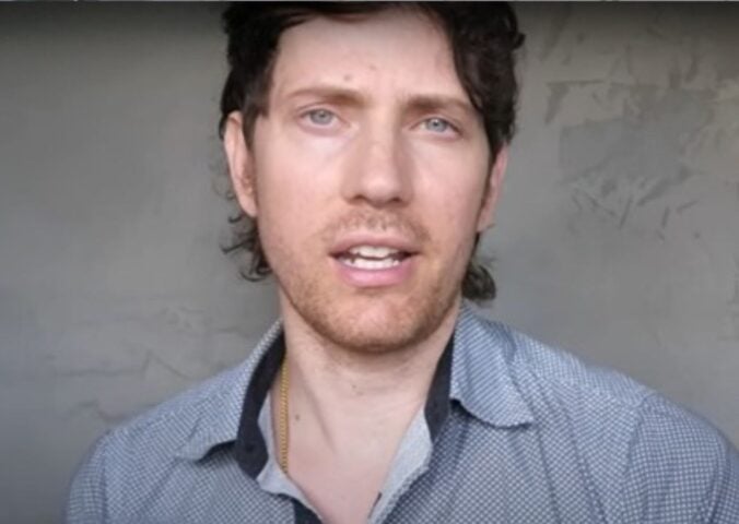 Mic the Vegan speaks to the camera in front of a grey background in a still from his video about vegan collagen