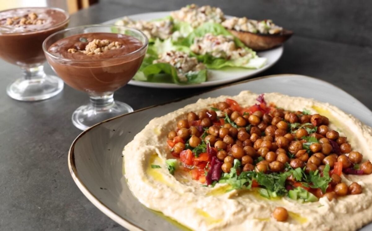 Shot of three vegan dishes made using chickpeas: hummus topped with roasted chickpeas, chickpea tuna salad, and aquafaba chocolate mousse