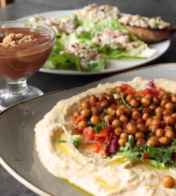 Shot of three vegan dishes made using chickpeas: hummus topped with roasted chickpeas, chickpea tuna salad, and aquafaba chocolate mousse