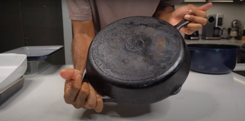 Malcolm Regisford holds a cast iron pan over a white kitchen counter