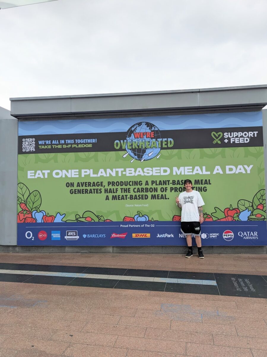 Photo shows Darrell Sawczuk of Plant Based News and Support + Feed standing in front of a large billboard advocating for one plant-based meal per day