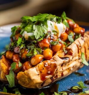 buffalo chickpeas on roasted sweet potato topped with coriander and coconut yogurt for vegan dinners where chickpeas are the start of the show