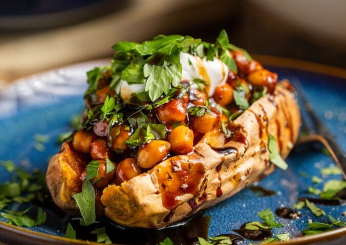 buffalo chickpeas on roasted sweet potato topped with coriander and coconut yogurt for vegan dinners where chickpeas are the start of the show