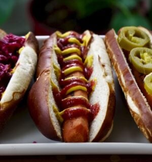 Three carrot dogs, one with red cabbage, one with ketchup and mustard, and one with jalepeno