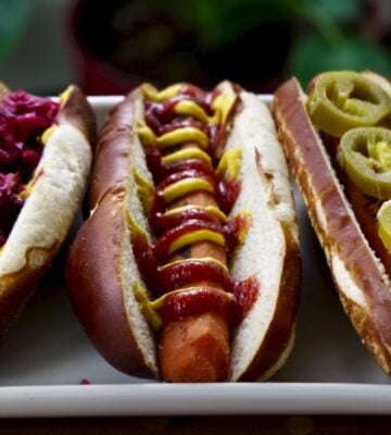 Three carrot dogs, one with red cabbage, one with ketchup and mustard, and one with jalepeno