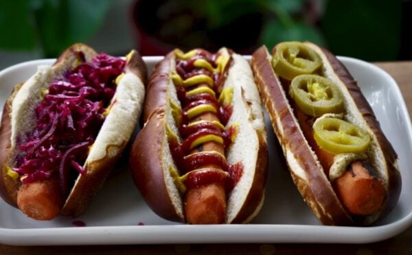 Three carrot dogs, one with red cabbage, one with ketchup and mustard, and one with jalepeno