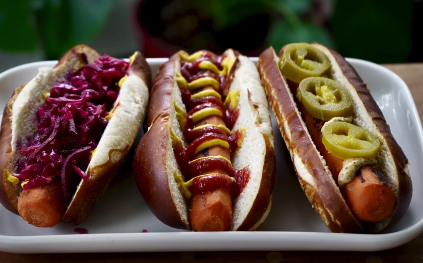 Three carrot dogs, one with red cabbage, one with ketchup and mustard, and one with jalepeno